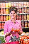 A woman in a supermarket holding tomatoes