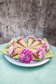 Pink carnations in ice-cream cones arranged in circles on green napkin on plate
