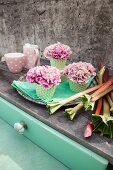 Carnations in cupcake cases on tray next to rhubarb stalks