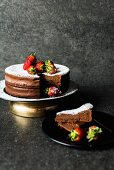 Chocolate cake with icing sugar and strawberries, sliced