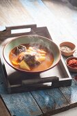 Steaming goulash soup in a bowl on a wooden tray