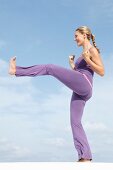 Junge blonde Frau in Sportkleidung macht Gymnastik am Strand