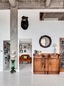 Concrete ceiling, eclectic furnishings and white wooden floor in living area of loft apartment