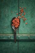 Goji berries on a spoon on a rustic surface