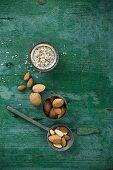 Almonds, shelled and unshelled, on a spoon and in a bowl, rustic wooden surface with slivered almonds