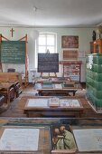 Blackboards, vintage school desks and open schoolbooks in classroom in school museum