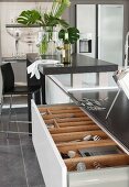 A kitchen island with a half-opened drawer and a view of a cutlery divider