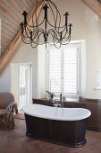 Free-standing bathtub and chandelier in attic bathroom