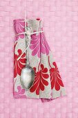 Vintage spoon on floral linen napkin on pink place mat