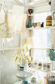 Porcelain containers arranges on white wooden shelves in window