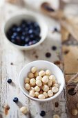 Macadamia nuts and blueberries in bowls on a rustic wooden surface