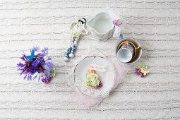 A retro place setting decorated with flowers on a knitted tablecloth