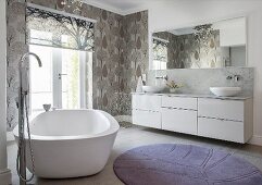 Free-standing bathtub and patterned wallpaper in elegant bathroom