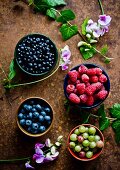 Bowls of fresh summer berries (raspberries, gooseberries and blueberries)