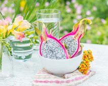 A halved pitahaya (dragon fruit) in a bowl on a garden table