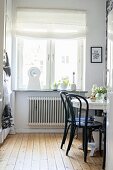 Black chairs at round white table in front of kitchen window