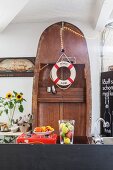 Wooden boat stood on end behind kitchen counter decorated with lifebelt and fairy lights