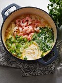Creamy coconut stew with rice noodles, prawns and spring onions