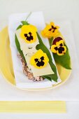 Slices of bread topped with cheese, wild garlic leaves and pansies