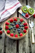 A green smoothie bowl with kiwis, raspberries, blueberries and chia seeds