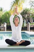 An older woman meditating by a swimming pool