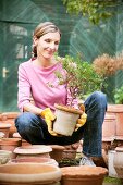 Smiling woman holding potted plant in garden