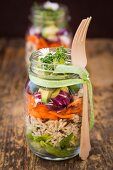 Springtime layered salads in glasses with rice, vegetables and daisies