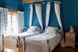 Schlafzimmer mit zwei Einzelbetten und weißen Baldachinen an blauer Wand