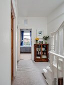 Staircase with turned balusters and antique display case in hallway