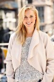 Junge blonde Frau in Grobstrickpulli und heller Fleecejacke