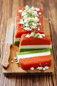 Tri-coloured terrine with tomatoes, cream cheese and green peas topped with feta cheese