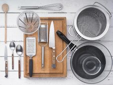 Kitchen utensils: a pan, a pot, a sieve, a grater, knives, cutlery and a measuring jug
