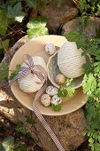 Easter eggs covered in cord and quail's eggs on plate and in bowl