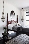 Bett in Kolonialstil mit geschnitztem Betthaupt, beidseitig Pendelleuchten im Schlafzimmer