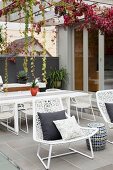 Outdoor-Lounge mit weißem Essplatz unter gerankter Pergola