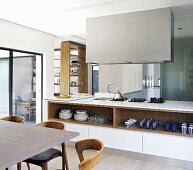 Island counter below extractor hood and open shelves seen past dining table