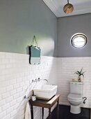 Two-tone wall with porthole window above toilet