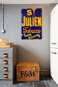 Old enamel advertising sign above wicker trunk