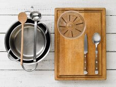 Küchenutensilien: Töpfe, Schöpfkelle, Holzlöffel, Messbecher und Besteck