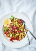 Courgette spaghetti with dried tomatoes, olives and walnuts