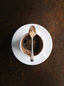 A cup of coffee with a spoon and sugar cube