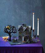 Gespenstisches Deko-Häuschen mit Baum und Kerzenleuchtern als Halloweendeko