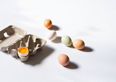 Frische Hühnereier neben Eierkarton mit aufgeschlagenem Ei