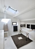 Skylight, shower area and free-standing white bathtub in attic bathroom