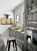 Fitted kitchen with moulded concrete frames, vintage wooden fronts and designer bar stools