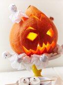 An illuminated Halloween pumpkin and ghosts as party decorations