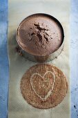 A chocolate cake in a baking tin with a heart drawn onto baking paper