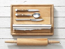 Assorted kitchen utensils: a rolling pin, aluminium foil, knives and a spoon