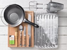Assorted kitchen utensils, a grill tray, a hand mixer, a frying pan and cutlery