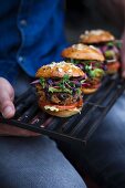 Mini burgers with bean patties, avocado cream, cucumber relish and cress